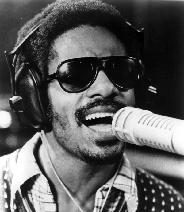 Black and White Picture of Stevie Wonder Singing. He is wearing sunglasses in the picture.