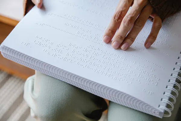 Picture of a hand reading a braille book