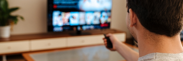 Muž s popcornem před televizí s ovladačem v ruce
