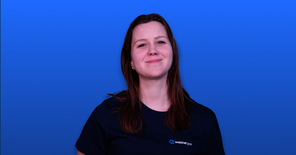 Person smiling, wearing a dark t-shirt with "webinar geek" logo, against a vibrant blue background.