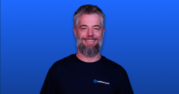 Smiling man with a beard in a "webinargeek" shirt, against a blue background.
