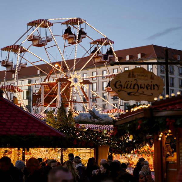 ferris wheel and market stalls at german christmas market during sunset