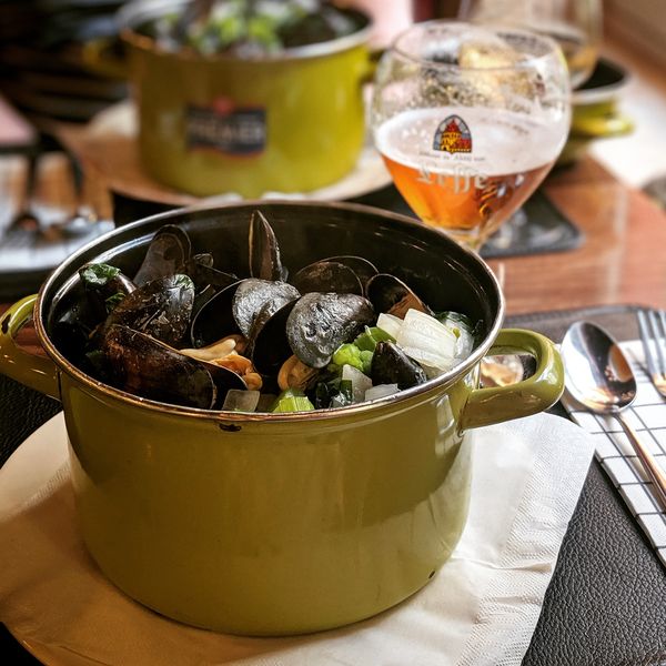 pot of mussels with a side of belgian beer at a table in bruges