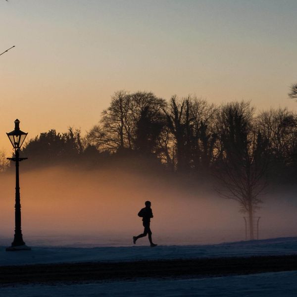 man running through foggy park at dusk