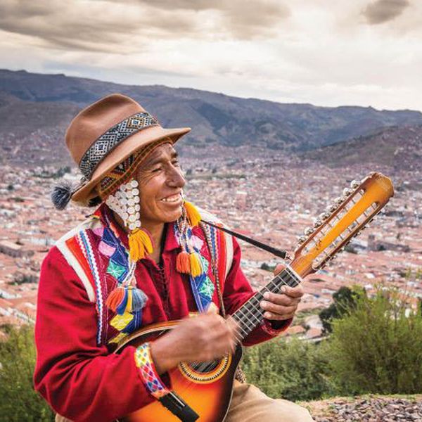 a peruvian musician playing an instrument wearing traditional textiles