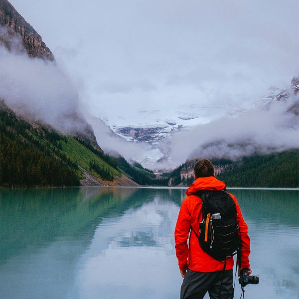 Traveler overlooks a mountain lake on a misty morning in the Canadian Rockies