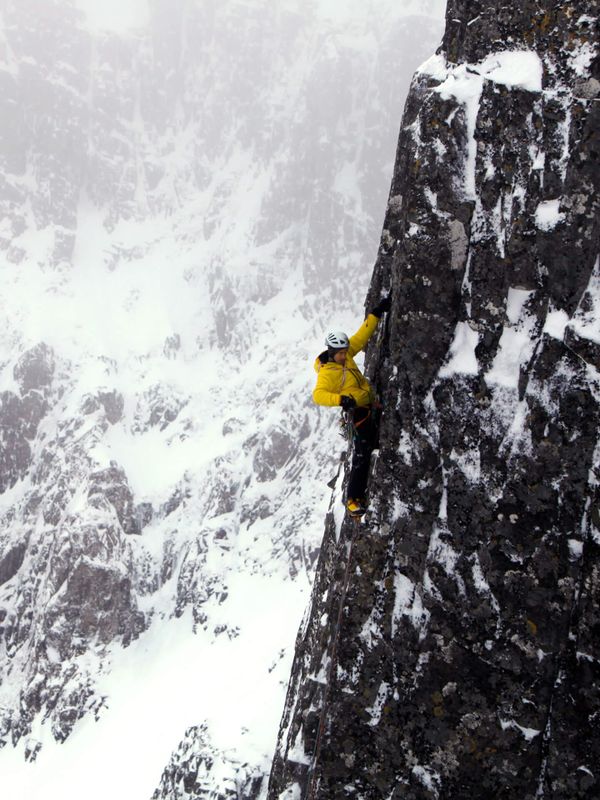 Andy climbing a mountain while wearing bright yellow to be seen in the snow