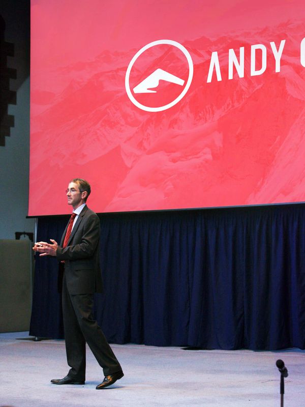 Andy Cave standing on stage and giving a motivational speech to a crowd.