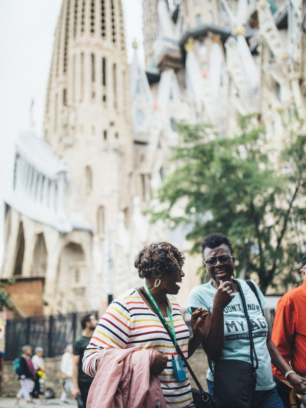 Two people walking and smiling in front of the Sagrada Familia, Barcelona