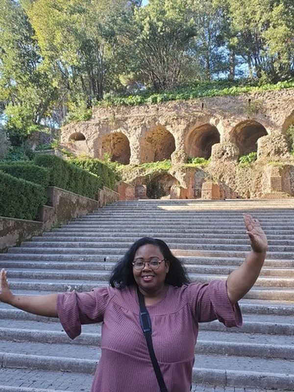 A woman standing in front of the stairs at Park Guell and smiling