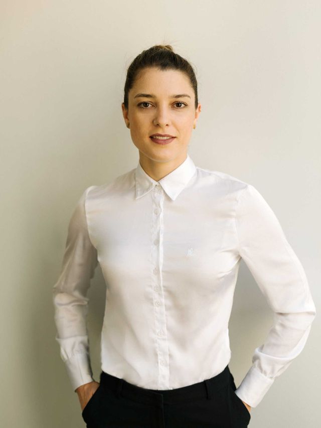 Bewerbungsbild einer Frau mit Händen in den Taschen mit weißer Bluse 
