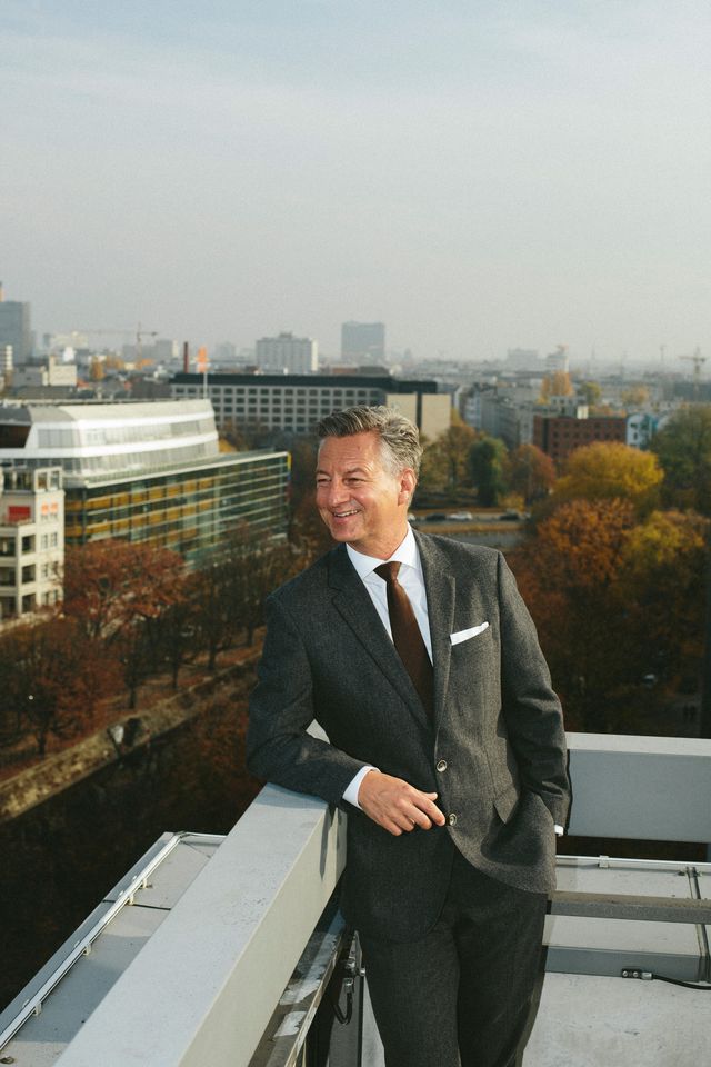 Businessportrait Mann steht im Anzug auf Dachterrasse Blick über Berlin