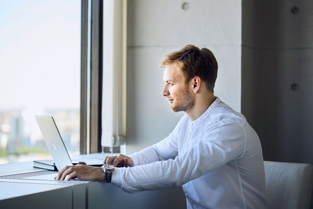 Businessportrait Mann sitzt mit Laptop am Fenster Corporate Fotografie