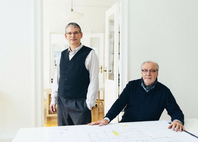 2 Architekten Businessportrait Berlin einer sitzt am Tisch einer steht
