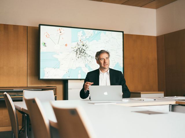 Mann sitzt am Tisch mit Karte im Hintergrund Businessfotografie Berlin
