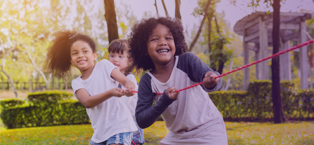 Kids smiling as they play tug-of-war