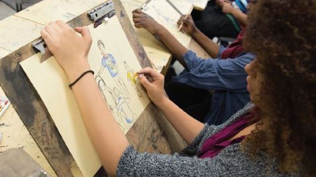 a student drawing on paper clipped to a clipboard