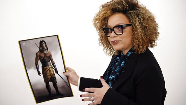 Ruth standing with a picture of a costume design from Black Panther.