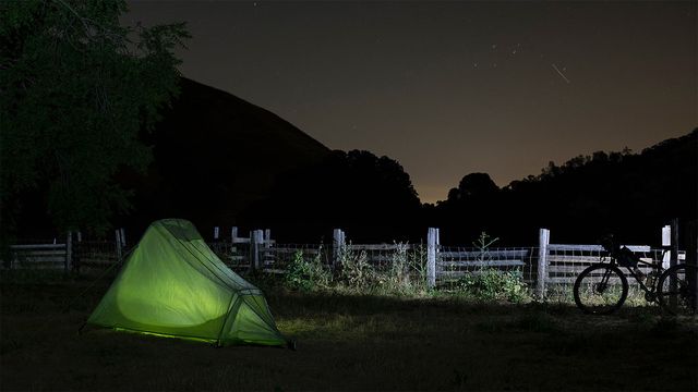 A bike parked next to a tent at night under the stars