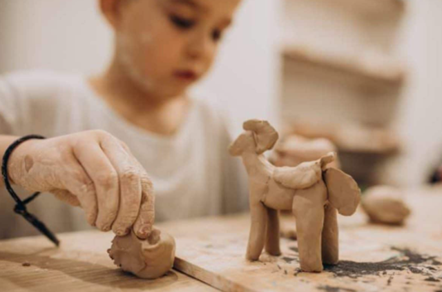 A boy using air dry clay to create a horse statue