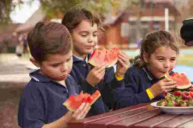 Children eating watermelon outdoors