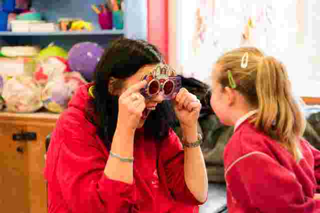 educator entertaining a kid with fun glasses