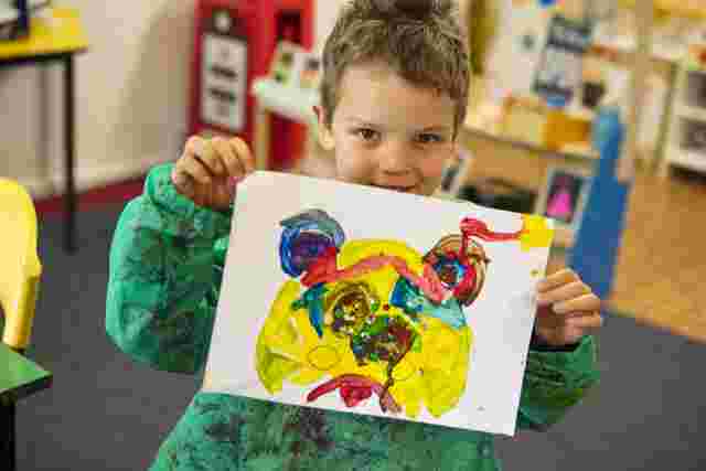 Boy holding up his painting
