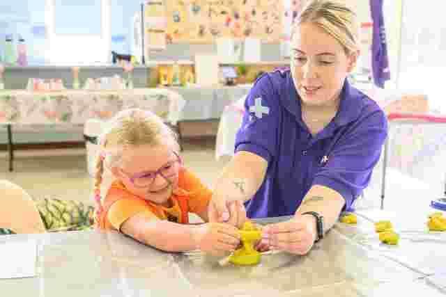 educator and child playing with clay with cross