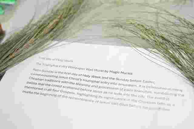 A close-up of a document describing Palm Sunday overlaid with decorative palm branches on a table.