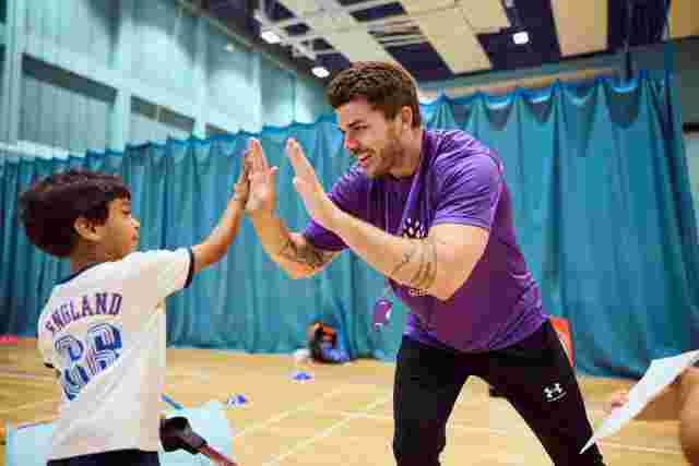 JAG staff high five with a child in a sports hall