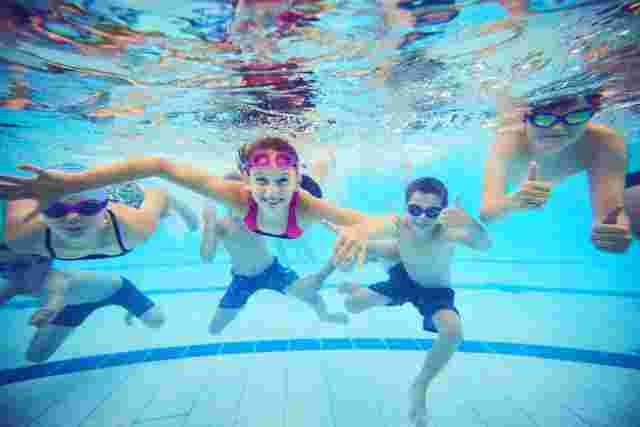 Group photo of children smiling under water in a swimming pool