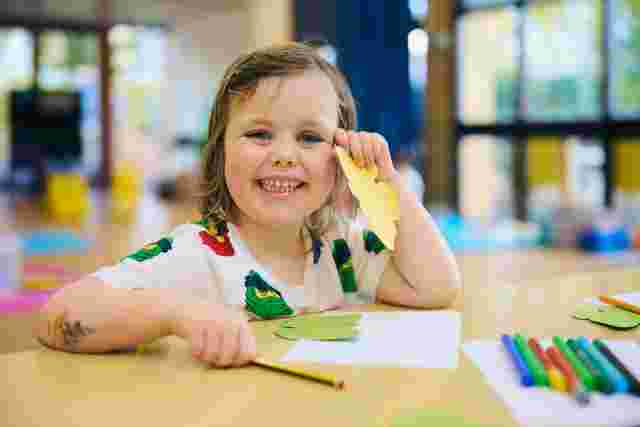 Child drawing and holding paper craft leaves