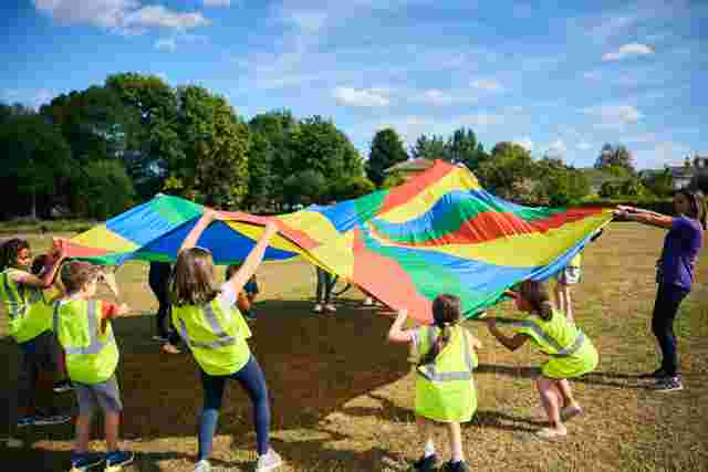 JAG staff and children playing parachute games on a field