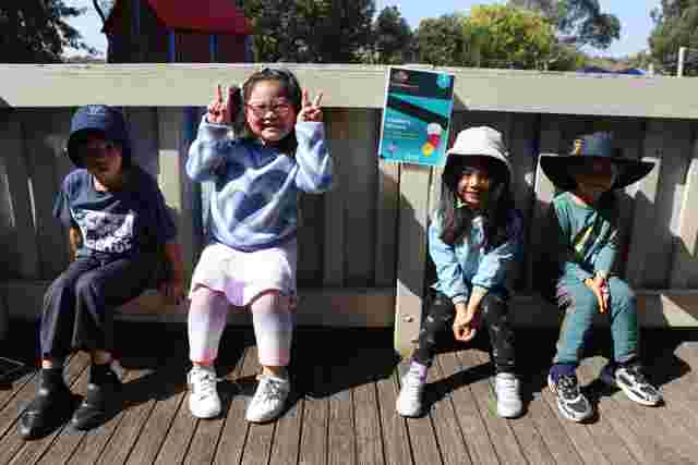 kids posing for a photo outdoors in the sun sitting on a ledge