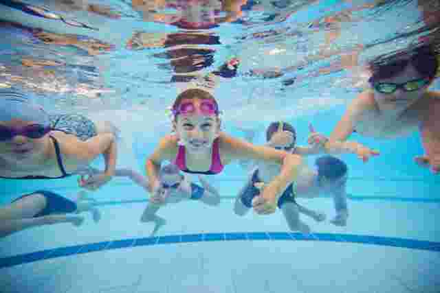 Group photo of children smiling under water in a swimming pool