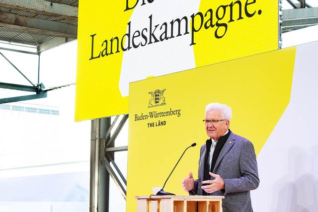 Ministerpräsident Winfried Kretschmann spricht auf einem Podium.