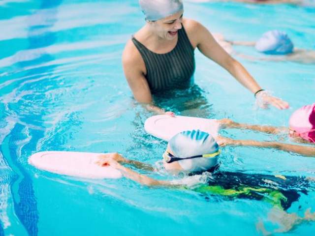 Frau bewegt sich gegen Rückenschmerzen und bringt Kindern Schwimmen bei