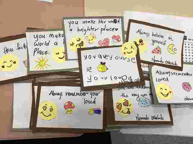 Handmade cards with positive messages and smiling emoji drawings, featuring phrases like "You make the world a brighter place" and "Always believe in yourself."