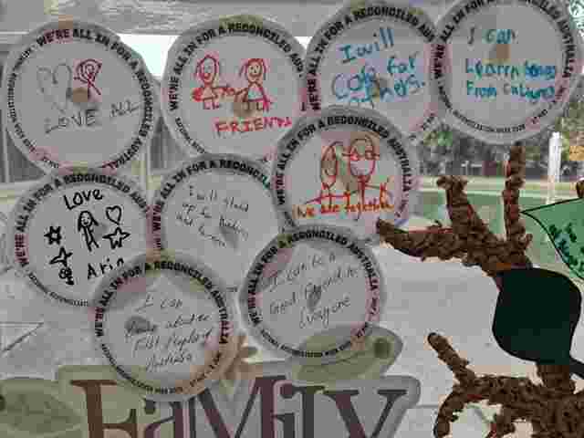 Paper circles with drawings and messages like "Love All" and "I will care for others" are displayed for National Reconciliation Week.