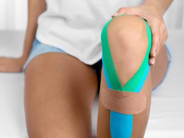 Frau hat Kinesio-Tapes am Knie wegen entzündeten Schleimbeuteln