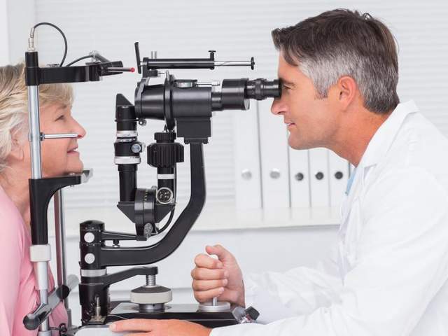Arzt begutachtet Augen einer Patientin mit Hilfe von Sehtestgerät