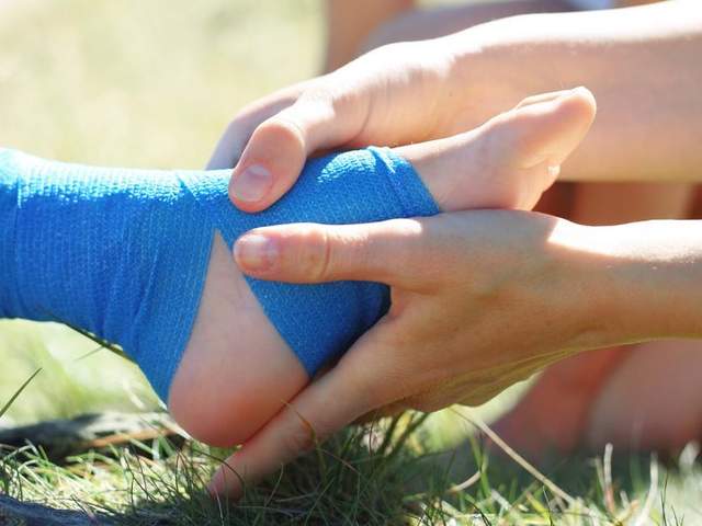 Frau hält geprellten bandagierten Fuß