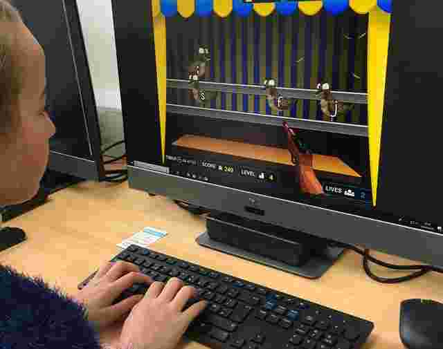A person plays a computer game featuring ducks on a shooting range. The screen displays score, time, level, and lives.