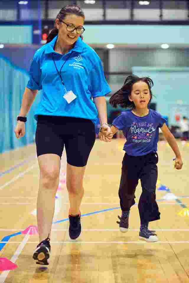 JAG Staff and Child running in a sports hall