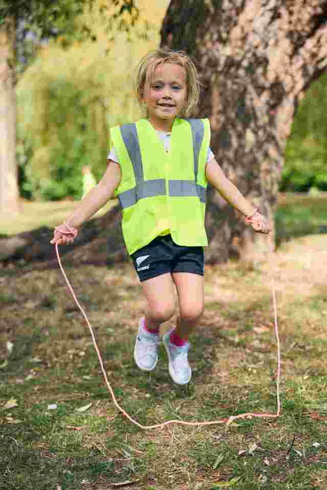 Child playing with a skipping rope with a smile outside