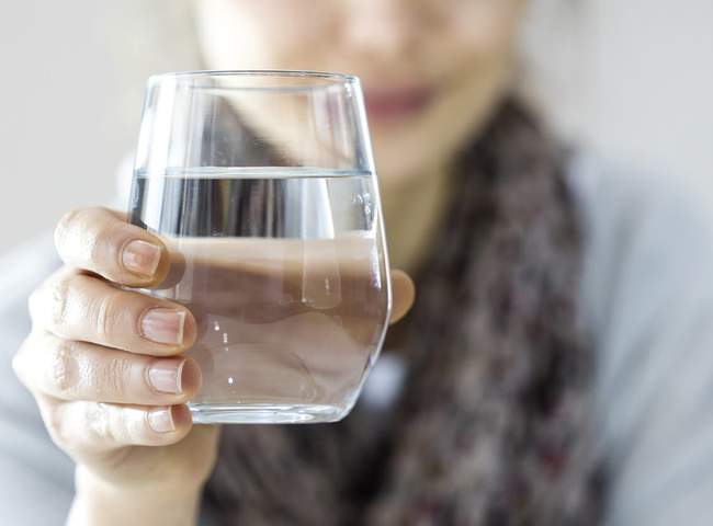 Frau hält Glas Wasser in der Hand zum Trinken