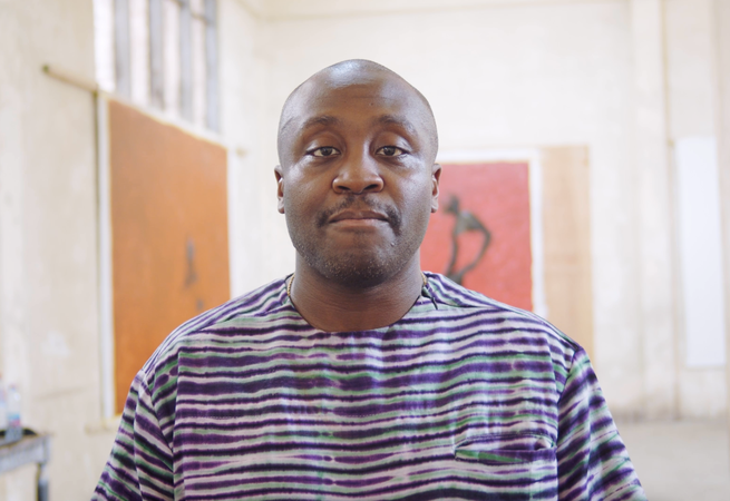 a man in a stripe shirt looking into the camera - video still from an interview with Larry Ossei-Mensah
