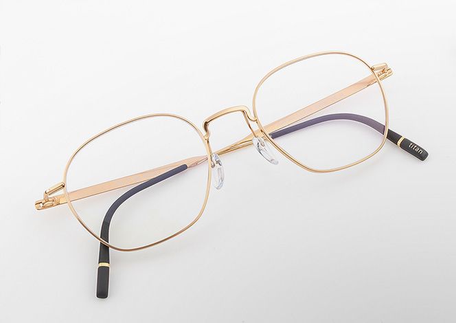 Pure Visionary titanium eyeglasses with an ultra-thin gold profile wire frame, softly geometric lenses, a sculpted bridge, and lightweight temples with black temple tips.
