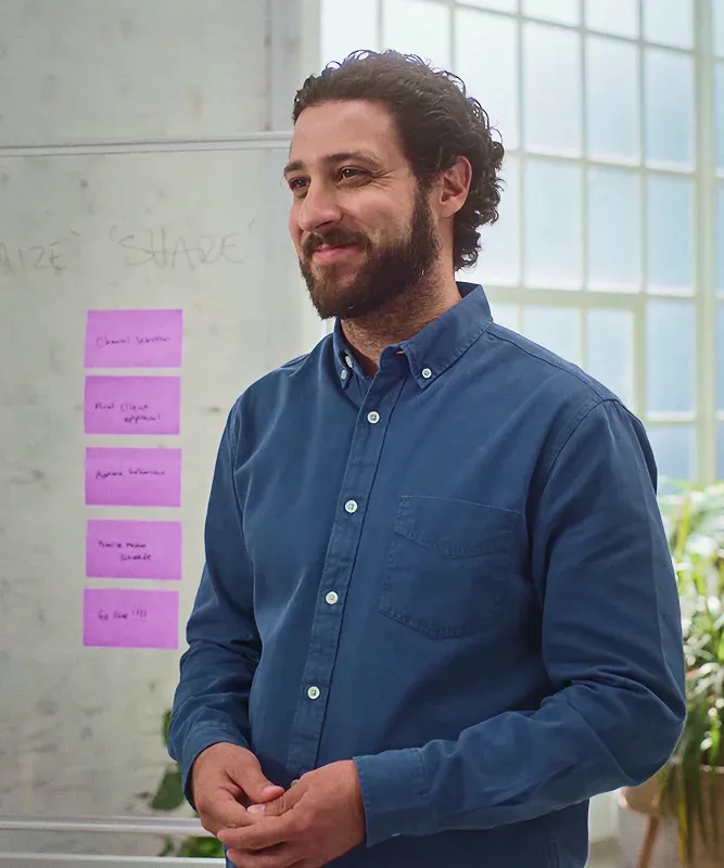 Man brainstorming a content sharing process using colourful sticky notes, mapping out ideas on a whiteboard.