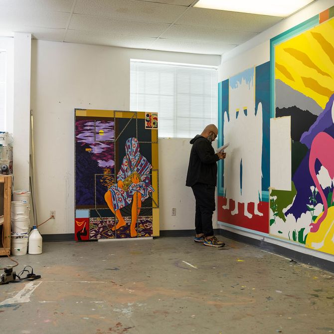 Amir Fallah looking at a large-scale painting on the wall of his studio